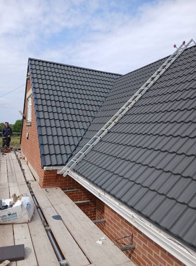 Long run of grey roof tiles fitted on a house extension